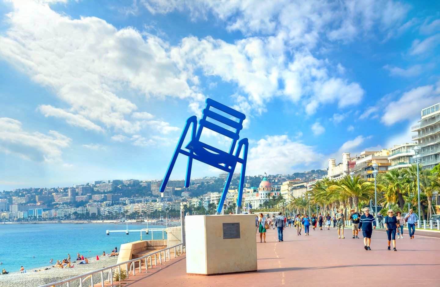 10 reasons to visit Nice in the Cote d'Azur People walking along the Promenade des Anglais past a sculpture of the famous blue chair (artist Sabine Geraudie)