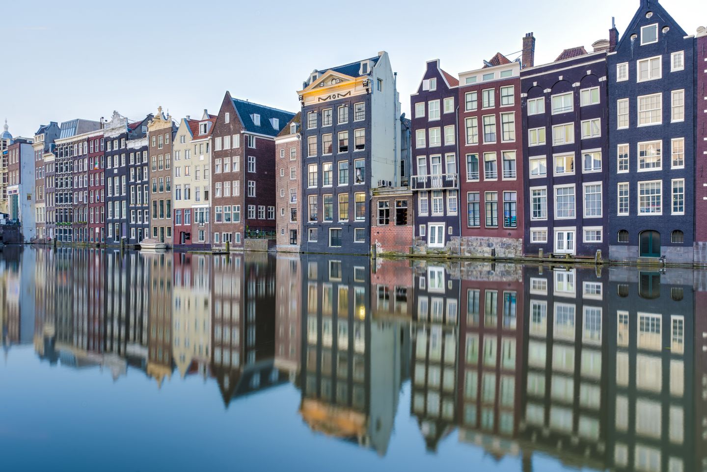 Where to stay in Amsterdam Reflections of buildings in the Damrak canal in Amsterdam, Netherlands